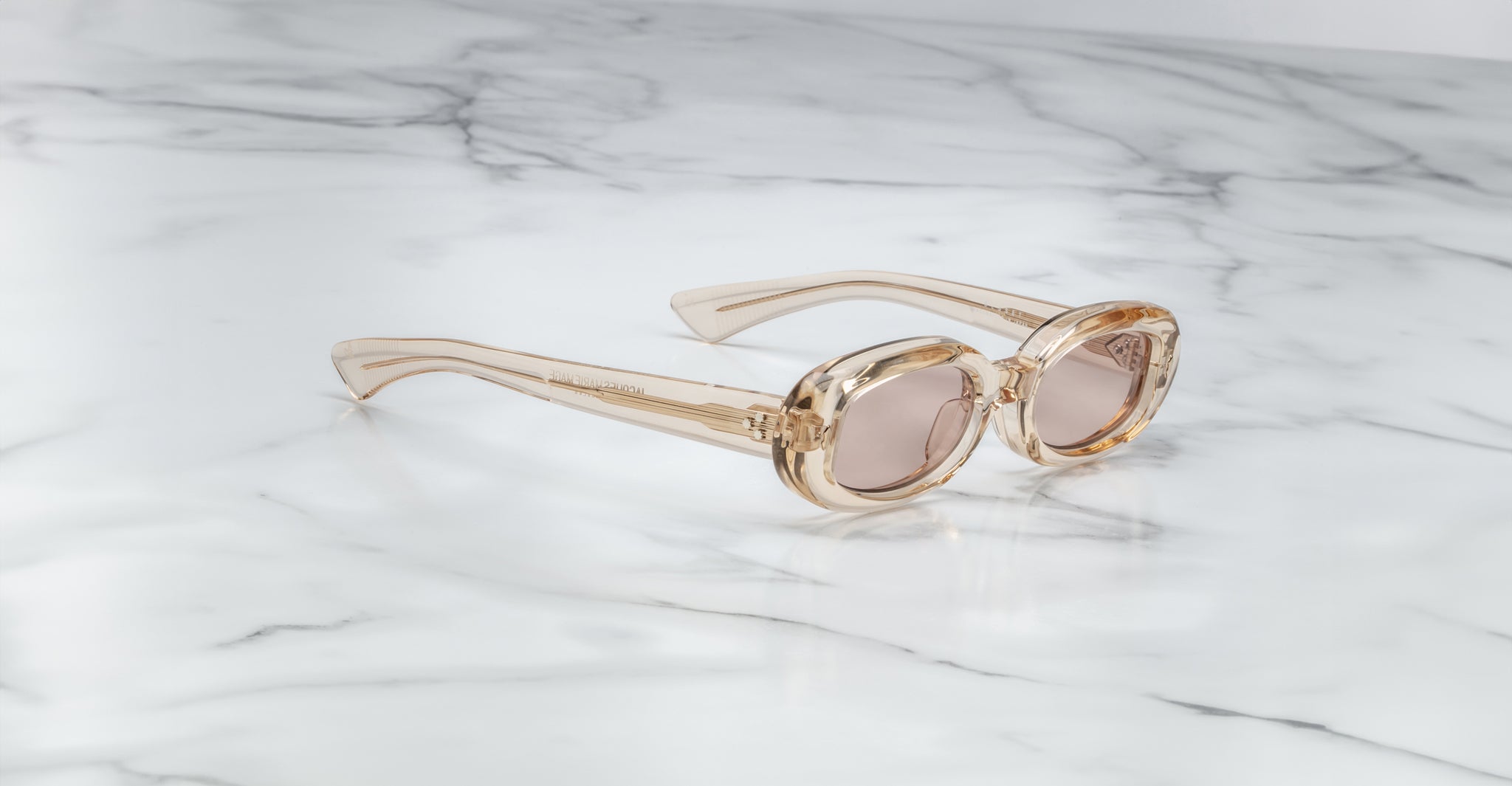 Jacques Marie Mage Besset sunglasses with clear frames and brown lenses, top view.