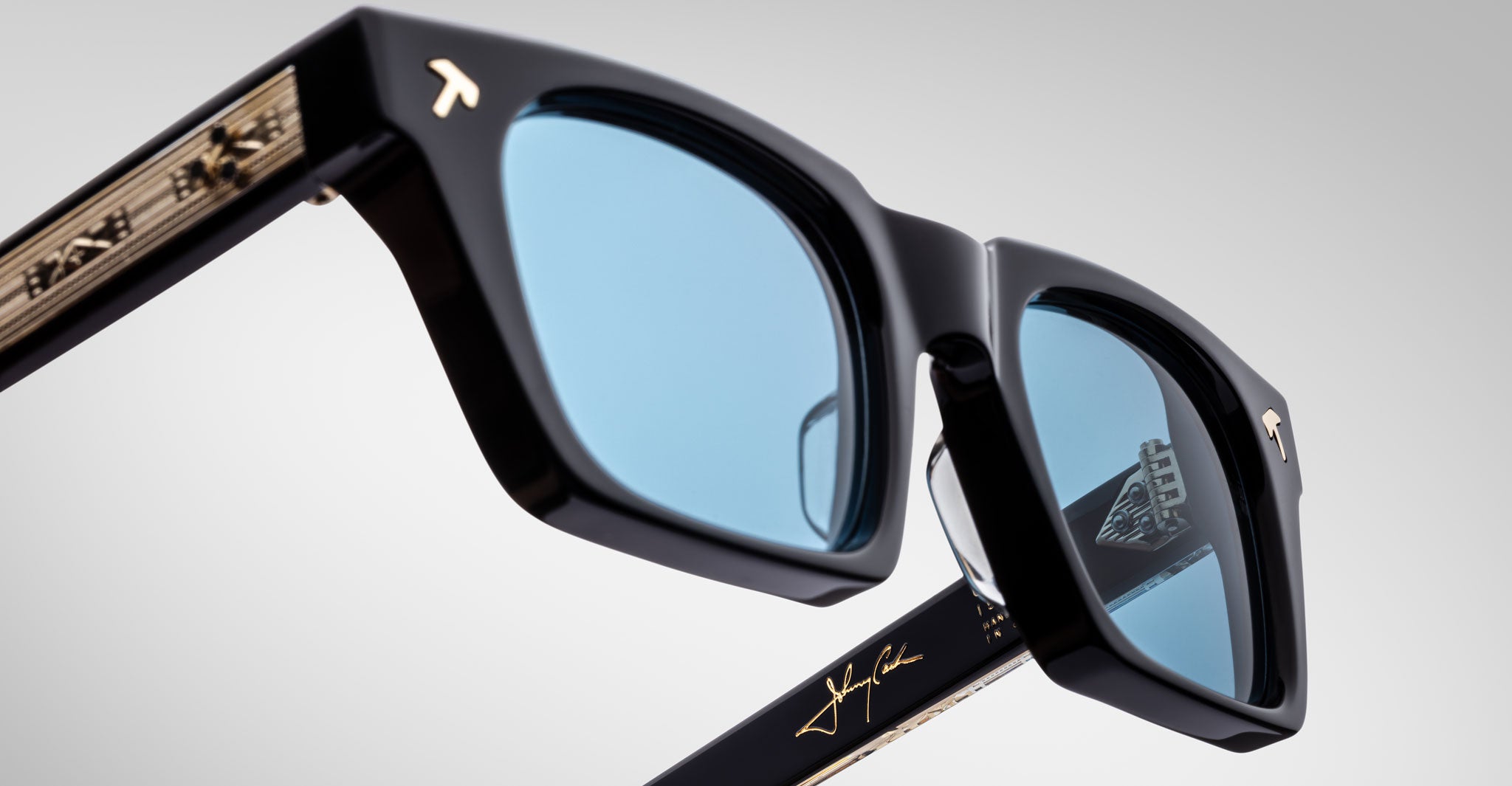 Close-up view of Jacques Marie Mage Quentin sunglasses featuring blue lenses, gold accents, and visible logo on temple and lens.
