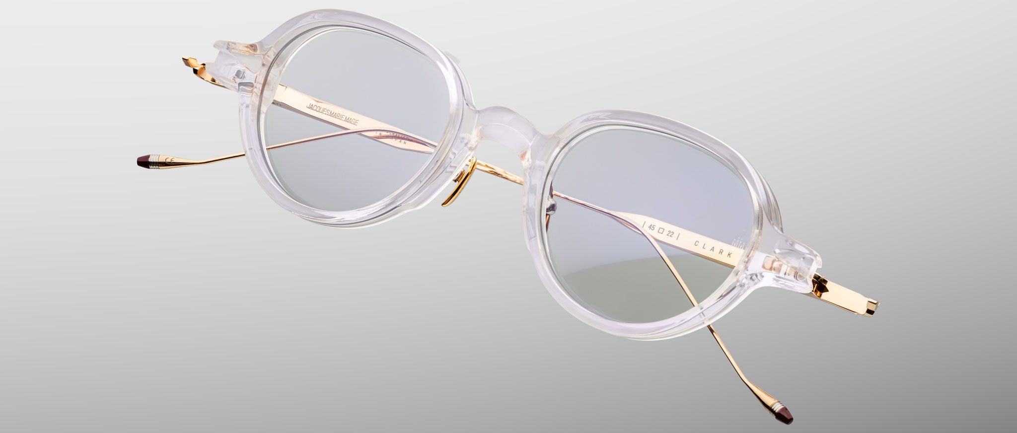 Jacques Marie Mage The Clark eyeglasses with clear frames and gold metal arms, shown from the front.