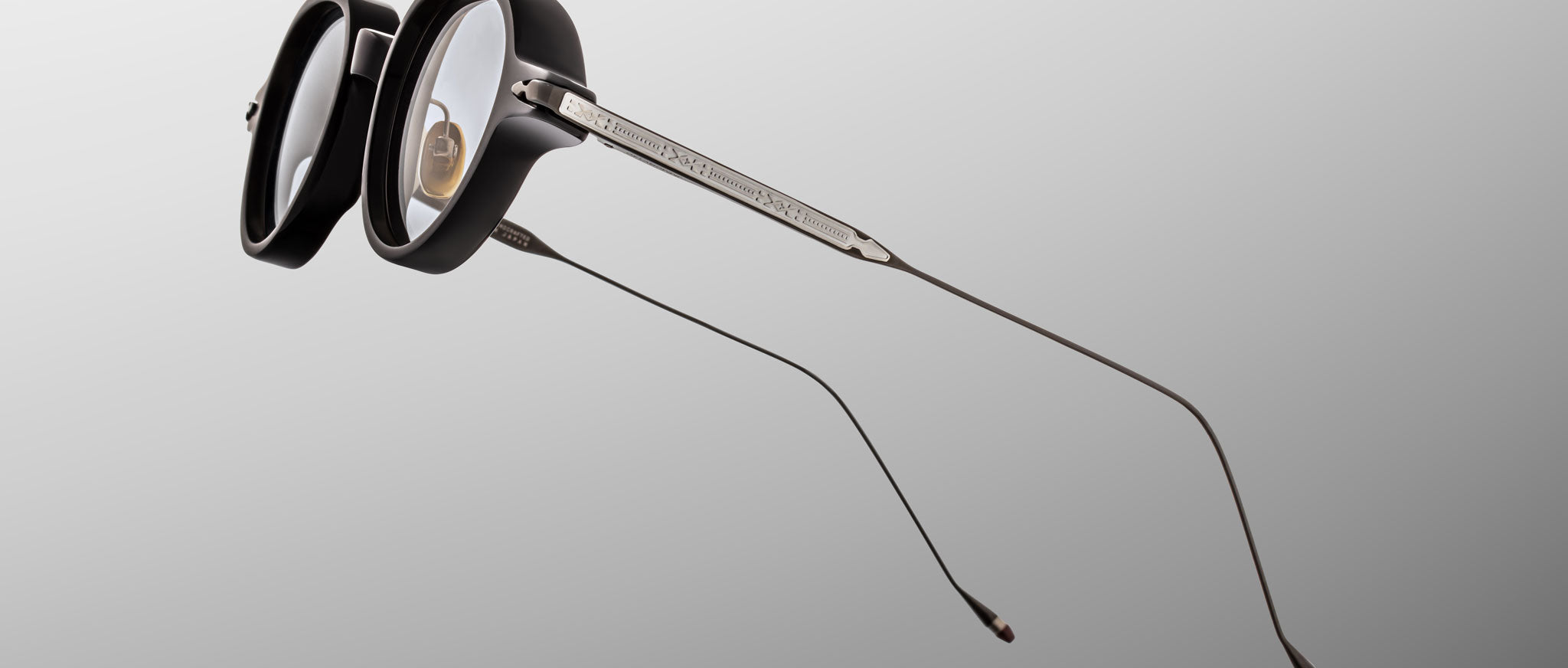 Jacques Marie Mage The Clark eyeglasses, thick black rims, slim metallic temples, shown from the front angle.