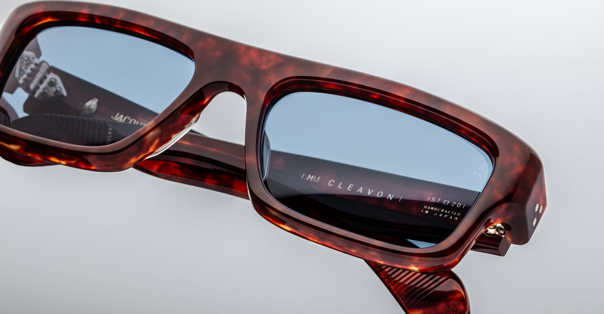 Close-up of Jacques Marie Mage Cleavon 57 rectangular sunglasses, tortoiseshell frame, blue lenses, and signature inner arm detail.