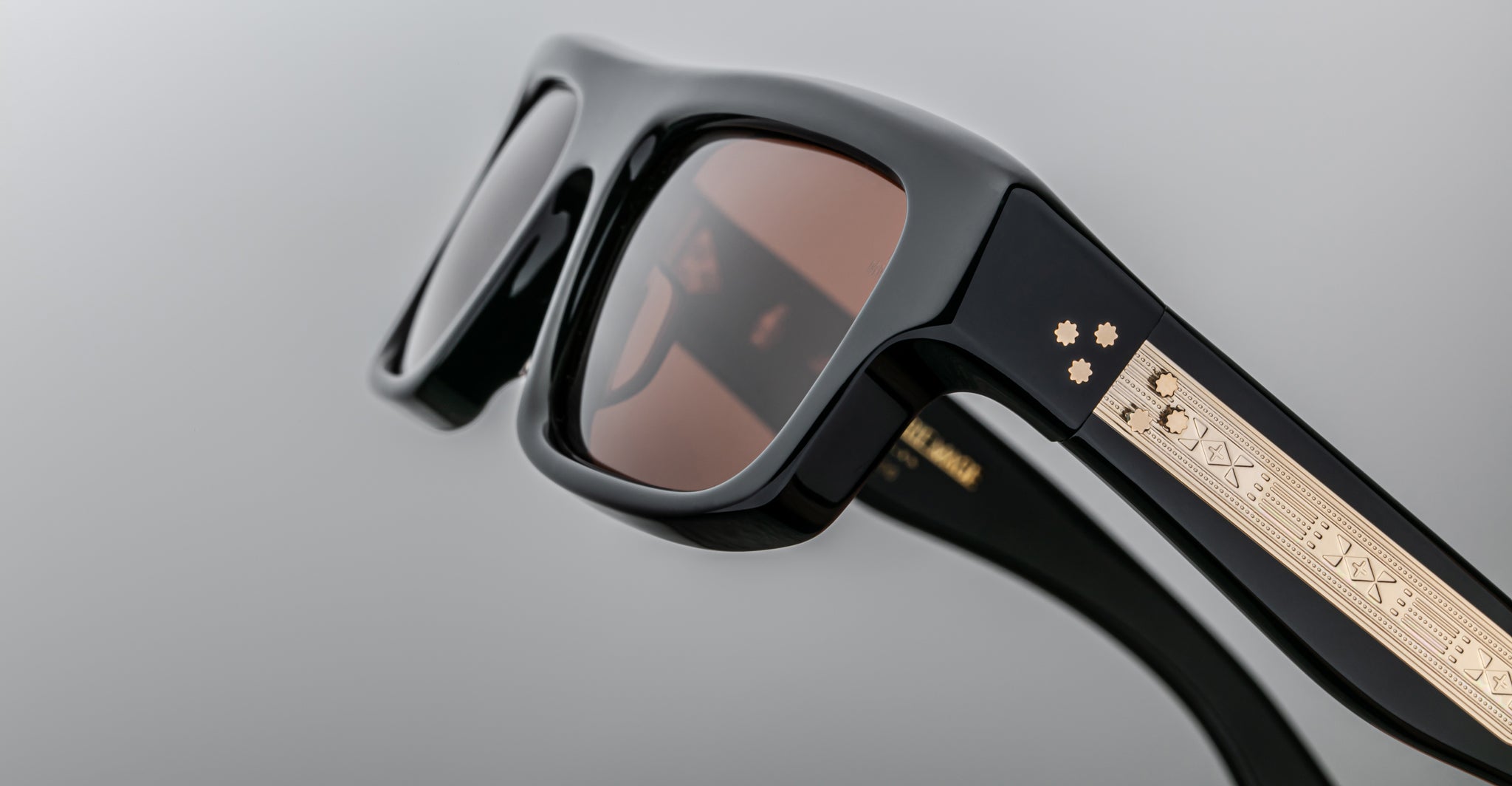 Close-up of Jacques Marie Mage Cleavon 57 black sunglasses, featuring gold accents and intricately designed temples, front angle view.