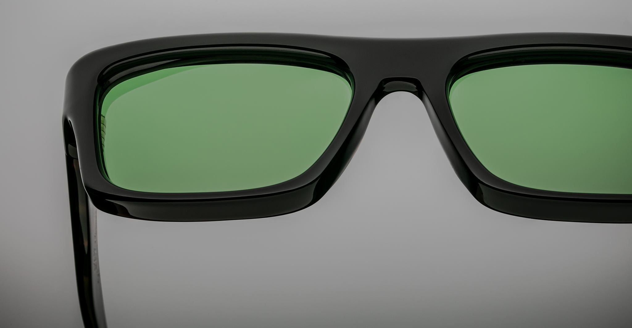 Close-up of Jacques Marie Mage Cleavon black eyeglasses featuring green-tinted lenses, viewed from the front.