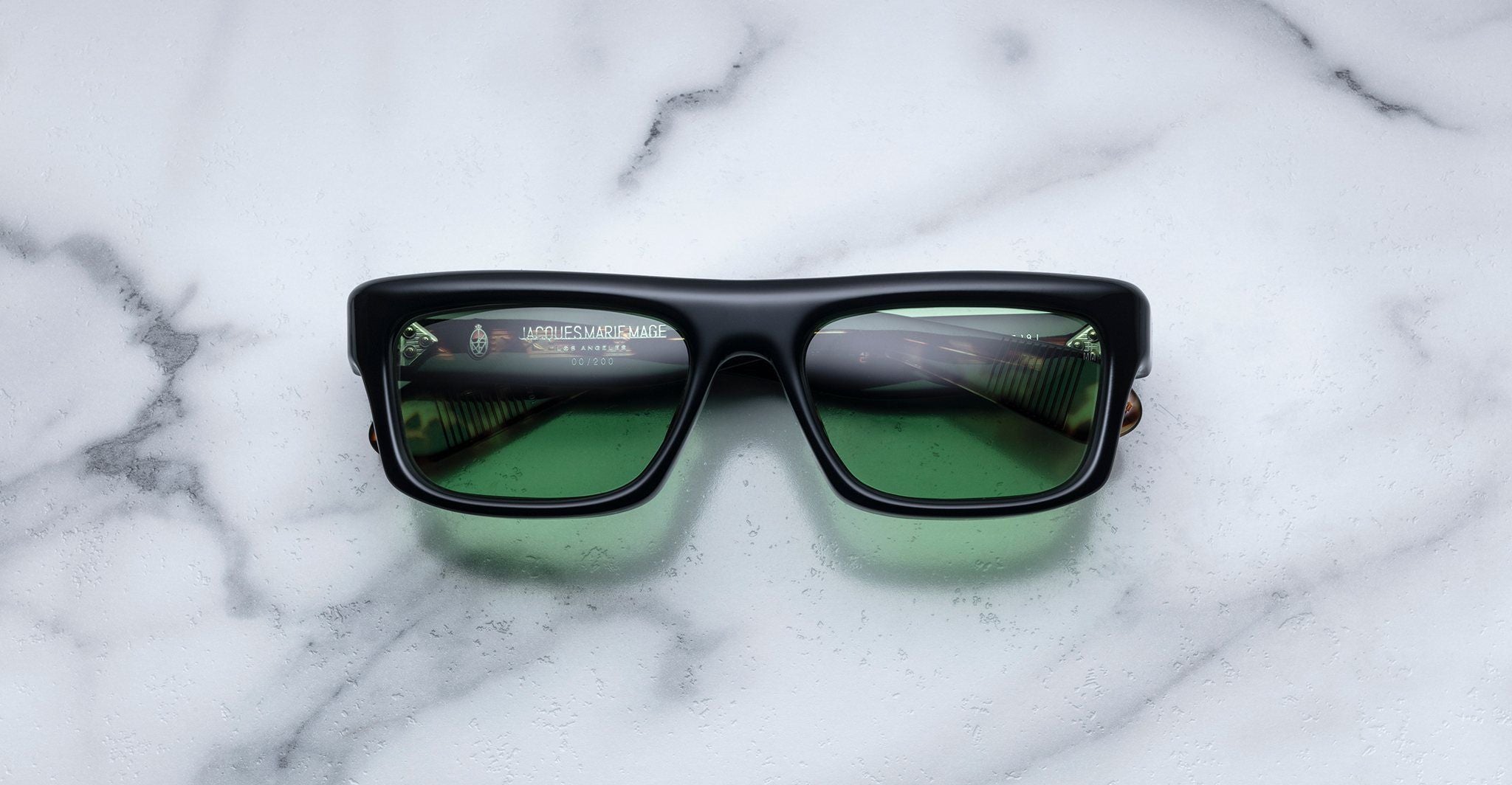Jacques Marie Mage Cleavon black rectangular sunglasses with green lenses, shown from above.