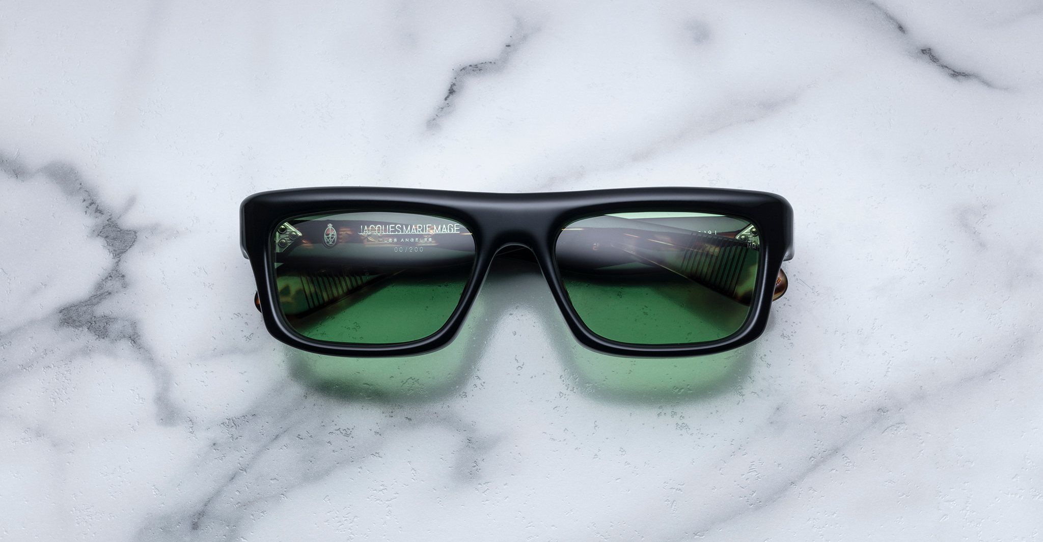 Jacques Marie Mage Cleavon black rectangular sunglasses with green lenses, shown from above.