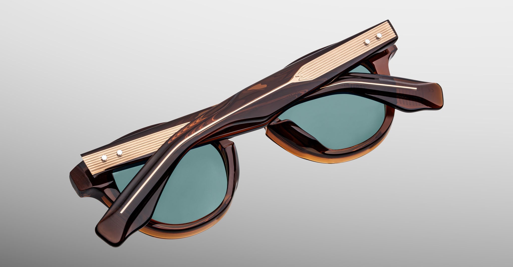 Jacques Marie Mage Clemens limited-edition sunglasses featuring dark tortoiseshell frames, round green lenses, and a metallic gold top accent, shown folded against a plain background.