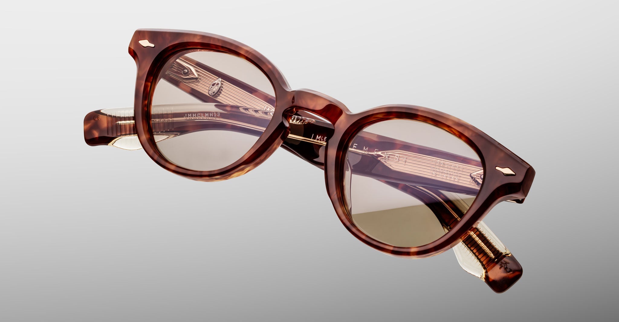 A pair of Jacques Marie Mage Clemens eyeglasses by Jacques Marie Mage, featuring round brown tortoiseshell frames and gold temple detailing, shown on a light gray background.