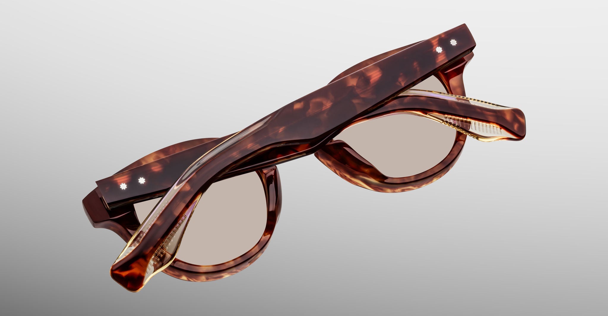 A pair of Jacques Marie Mage Clemens round-lens eyewear in brown tortoiseshell, folded against a plain gradient background.
