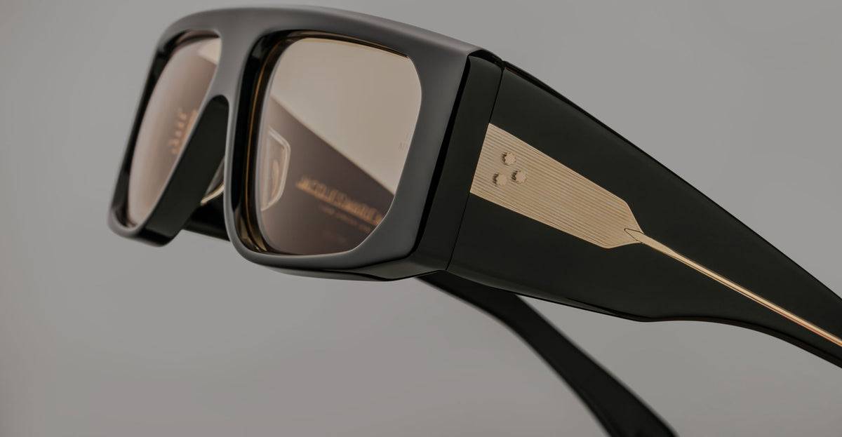 Jacques Marie Mage Cliff sunglasses, black frame with gold accents, UV-protected brown-tinted lenses, front view.
