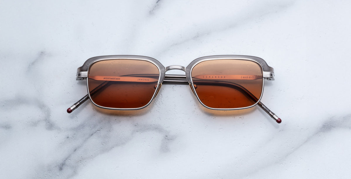 Jacques Marie Mage Comanche in tempest rectangular sunglasses with brown lenses and silver frames, top-down view.