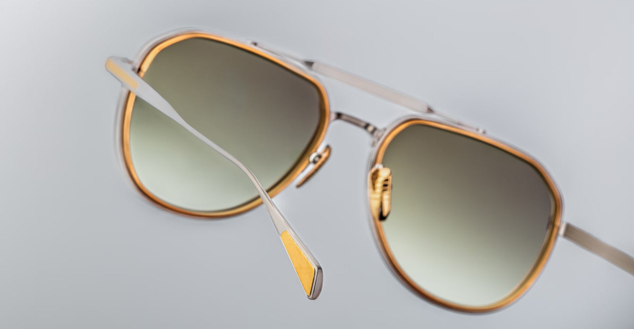 Close-up view of Jacques Marie Mage Commander sunglasses featuring gold and silver metal frames with gradient dark lenses, set against a plain light gray background.