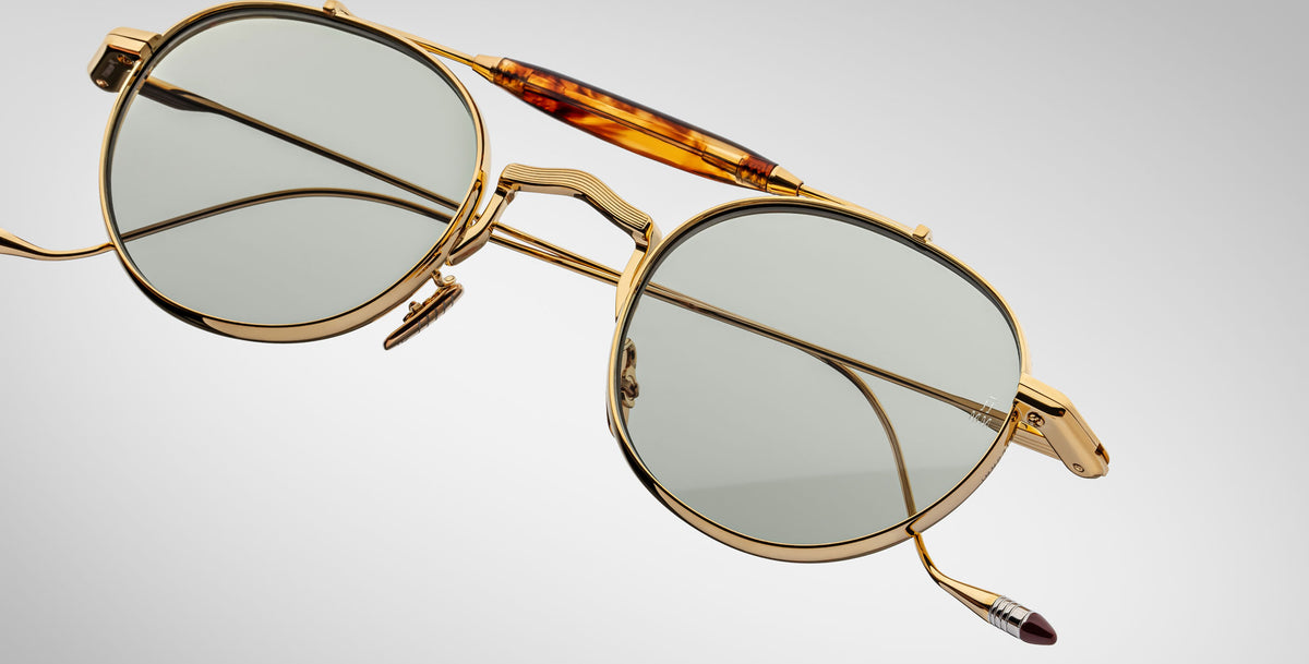 Detailed front view of the Jacques Marie Mage Dasan titanium sunglass in gold color with light grey lenses on a white background