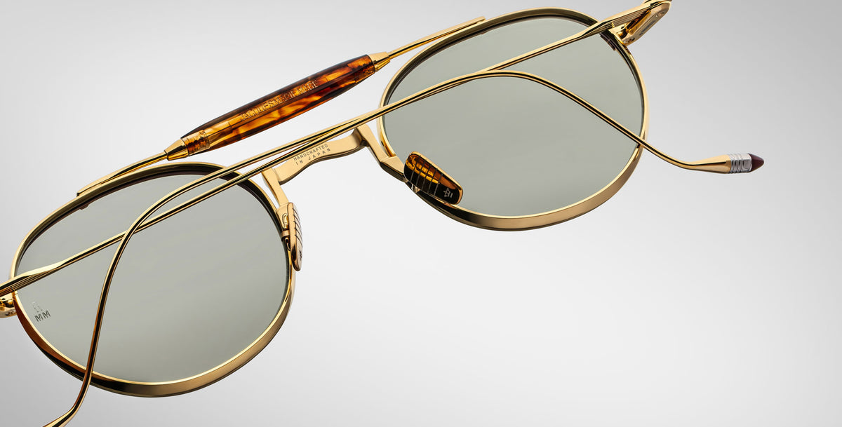 Back view of the Jacques Marie Mage Dasan titanium sunglass in gold color with light grey lenses on a white background