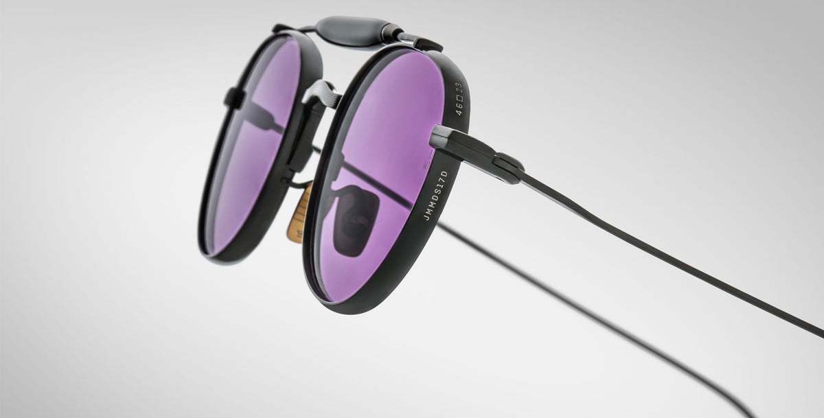 Detailed profile view of the Jacques Marie Mage Dasan titanium sunglass in black color with purple lenses on a white background