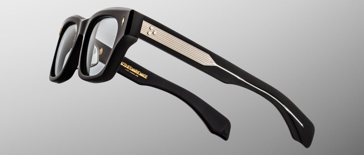 Jacques Marie Mage Dealan 53 black eyeglasses with gold accents and branding, front view.