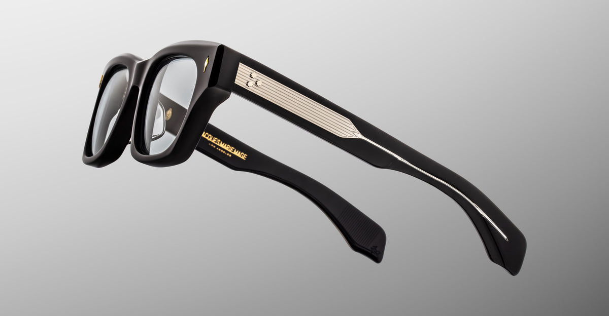 Jacques Marie Mage Dealan 53 black eyeglasses with gold accents and branding, front view.