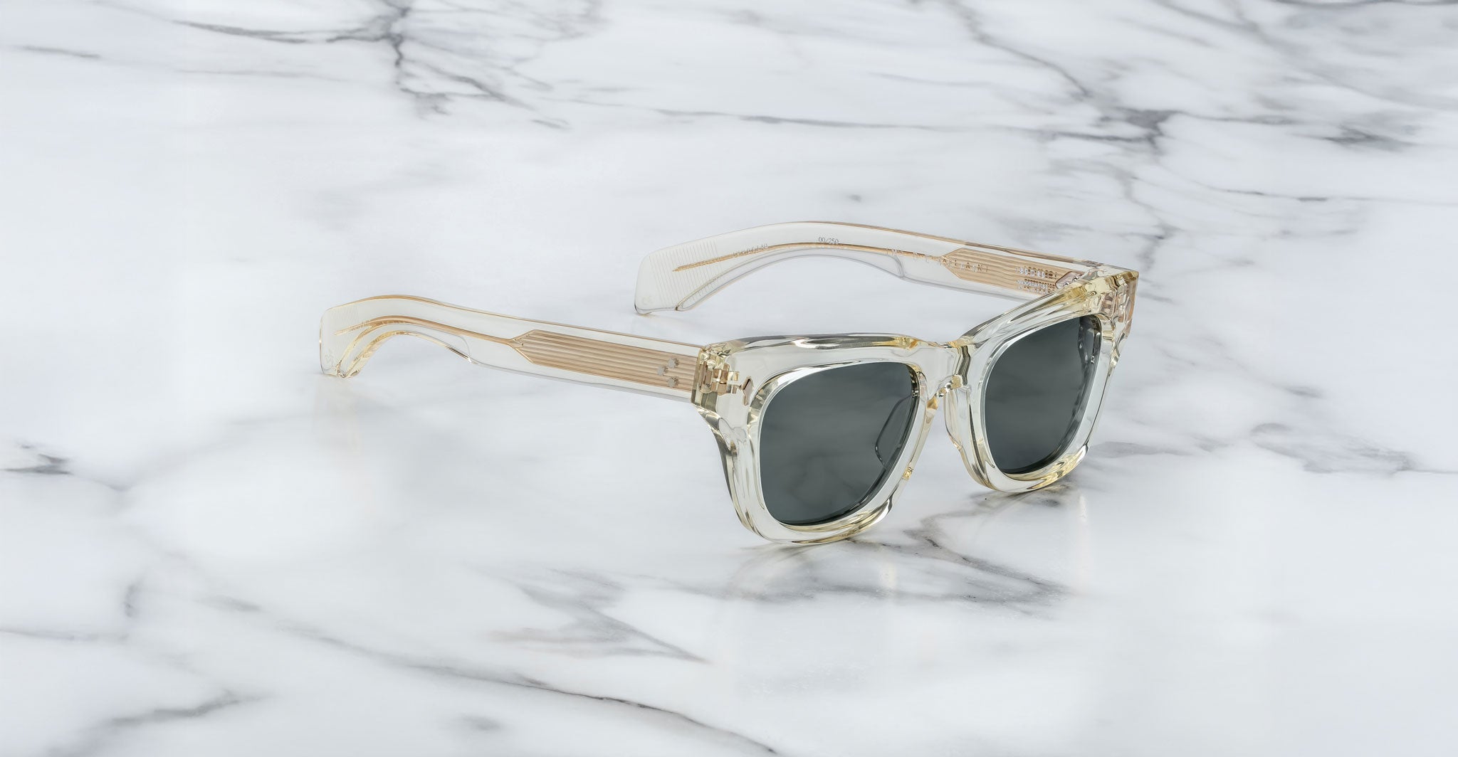Jacques Marie Mage Dealan sunglasses with clear frames and dark lenses, viewed from above.
