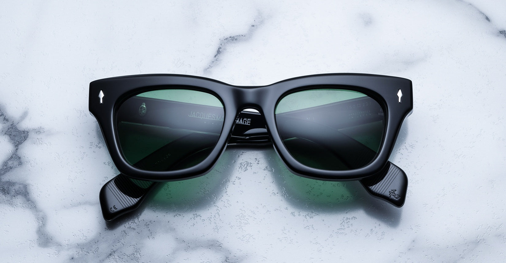 Jacques Marie Mage Dealan black rectangular sunglasses with green lenses, top view.