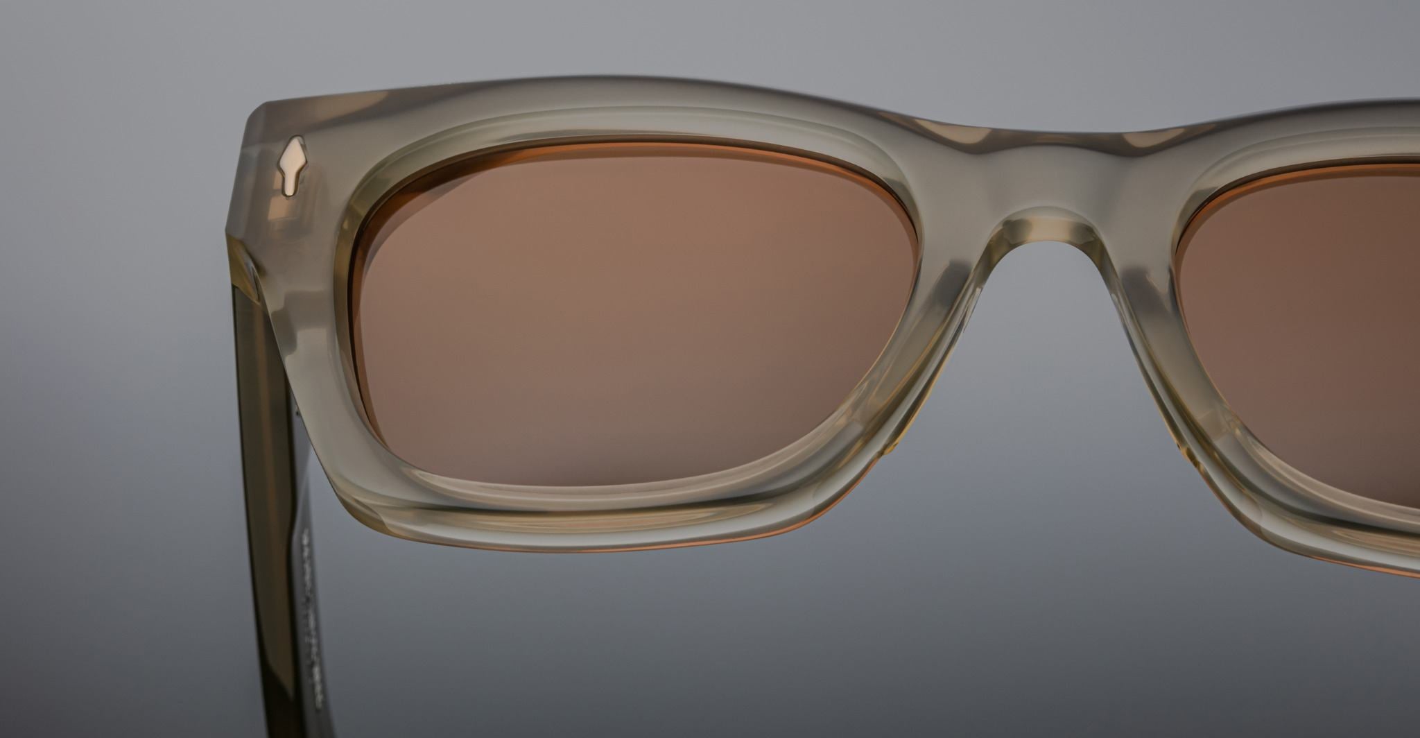 Close-up of Jacques Marie Mage Dealan rectangular sunglasses featuring light brown translucent frames and brown-tinted lenses.
