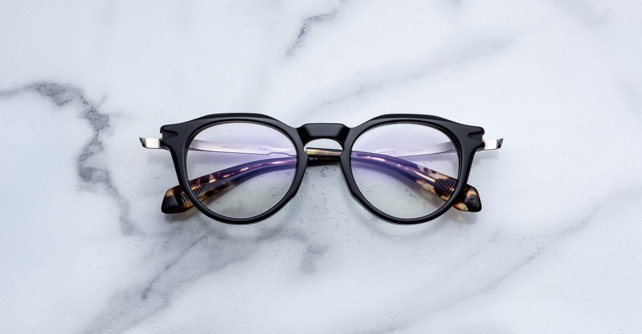 Jacques Marie Mage Desnos eyeglasses with round black frames and tortoiseshell arms, shown from above.