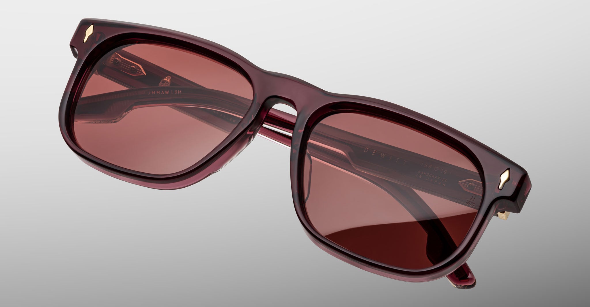 The Jacques Marie Mage Dewitt sunglasses feature rectangular frames in thick, dark red translucent acetate with matching tinted lenses, displayed against a plain light gray background.