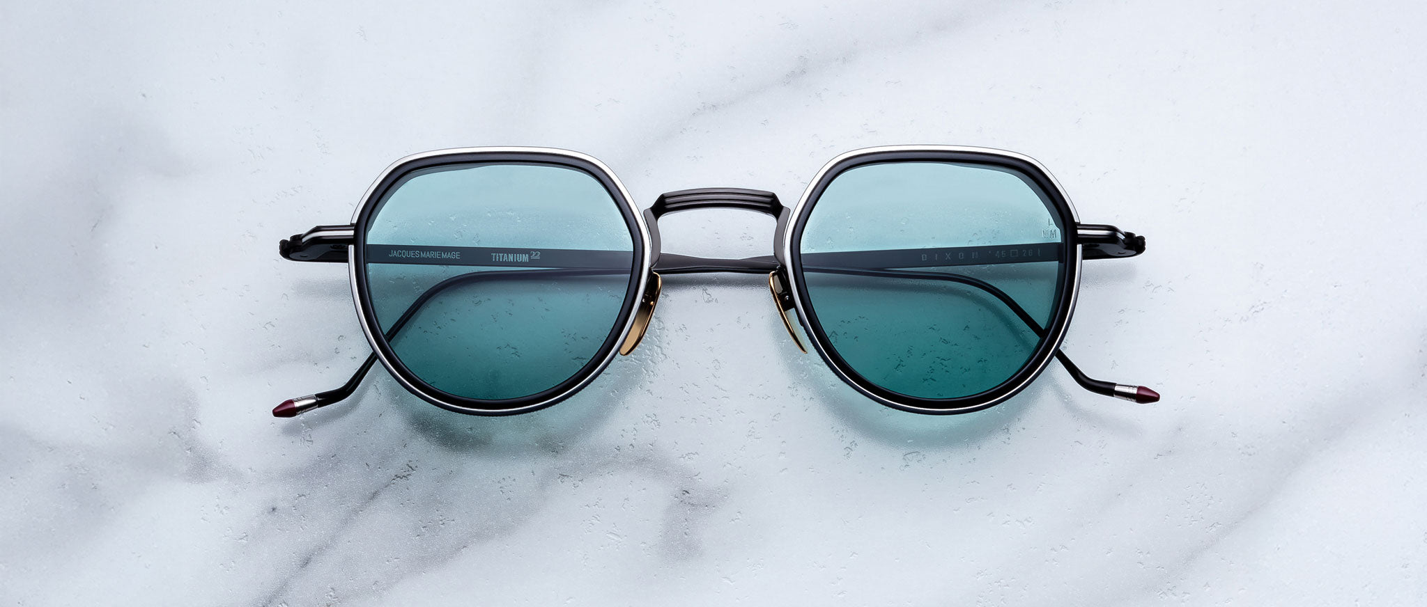 Jacques Marie Mage Dixon sunglasses with blue lenses and black frames, top view.