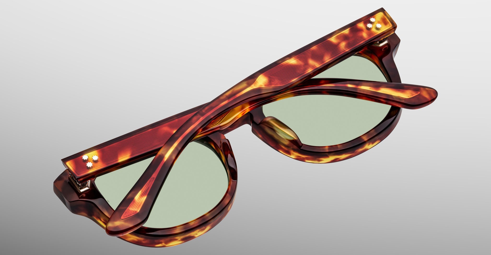 The Jacques Marie Mage Dr. Dream sunglasses, featuring luxury frames and green lenses, are shown folded from above against a plain background.