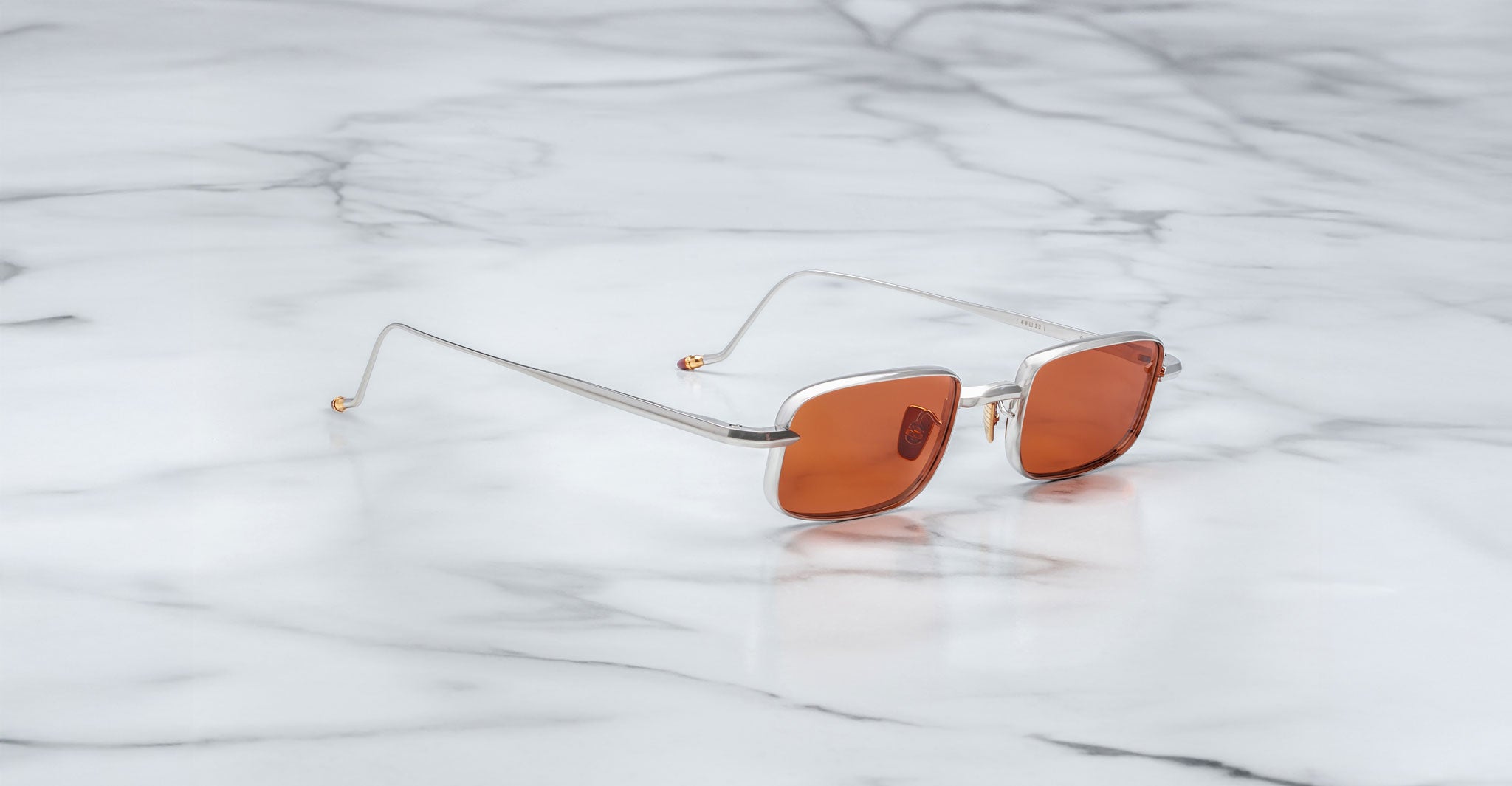 A pair of Jacques Marie Mage Dusk sunglasses on a marble surface.