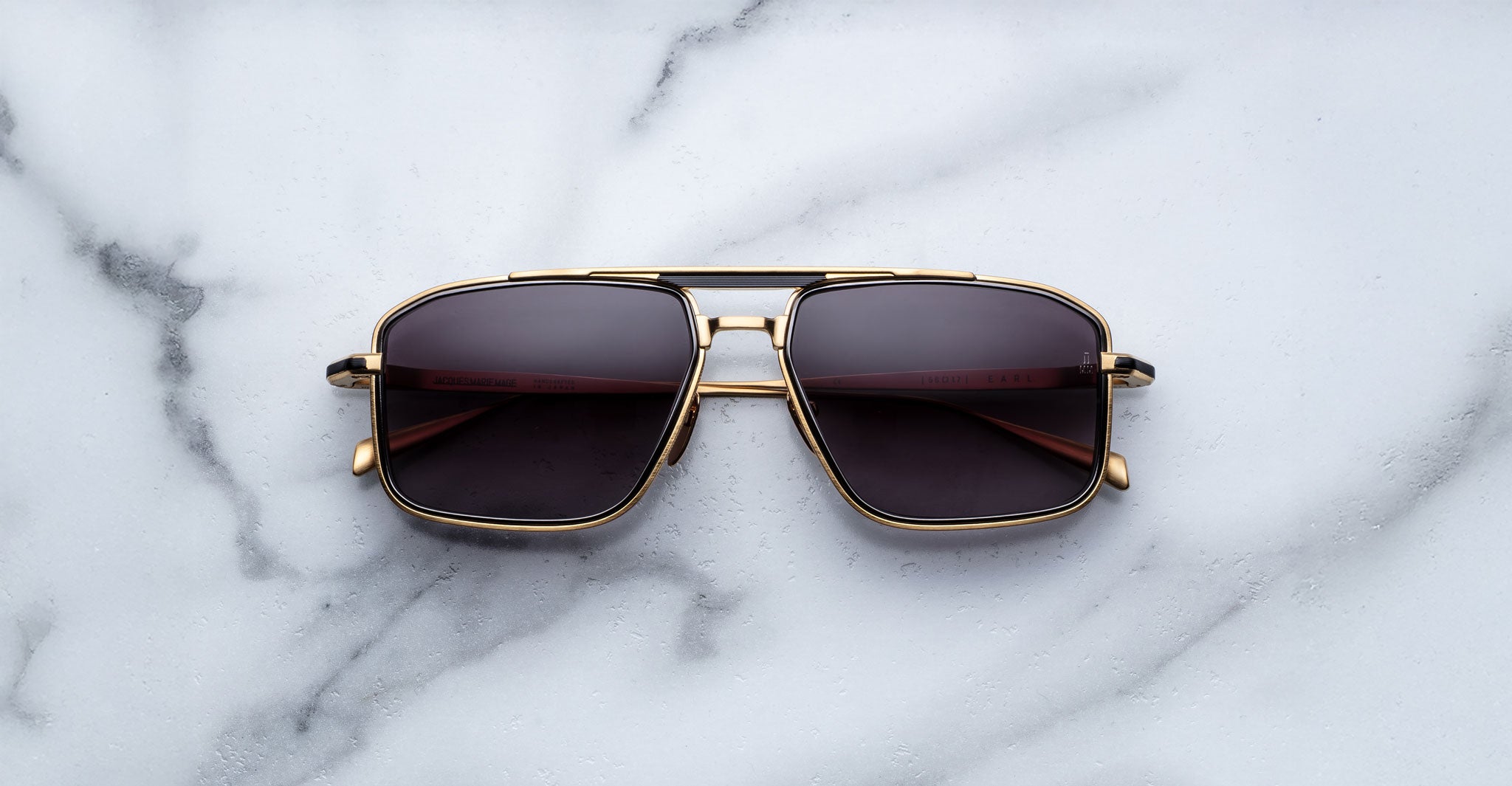 Jacques Marie Mage Earl gold aviator sunglasses with dark polarized lenses, top-down view.