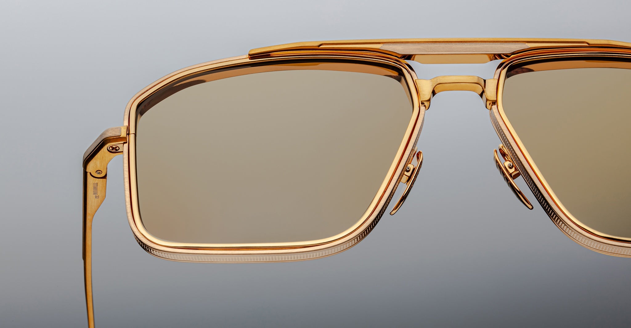 Close-up of Jacques Marie Mage Earl sunglasses with gold frames and polarized brown lenses, showing the front view.