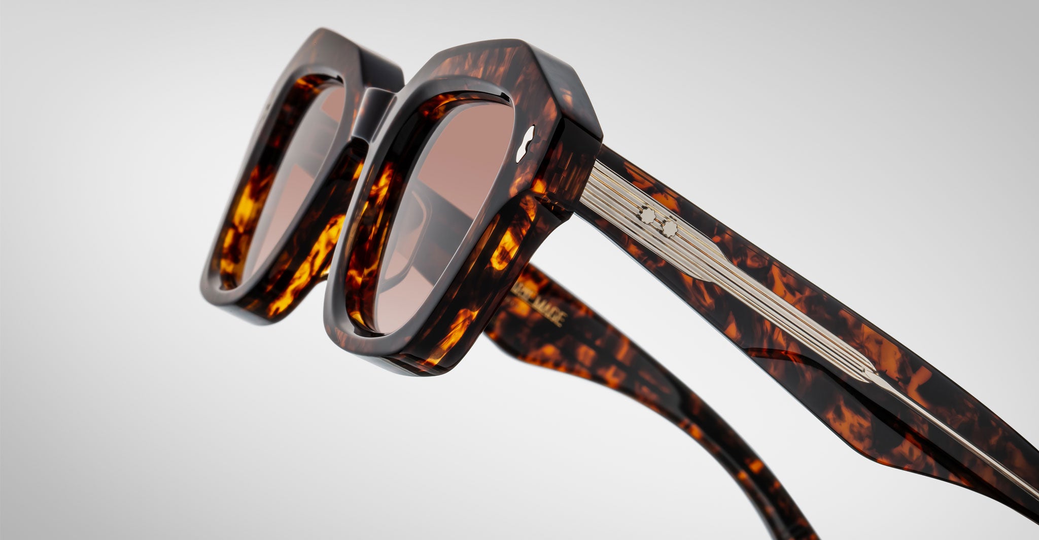 Detailed profile view of a pair of Jacques Marie Mage Eichler Havana color, thick-framed sunglasses with brown lenses on a plain background
