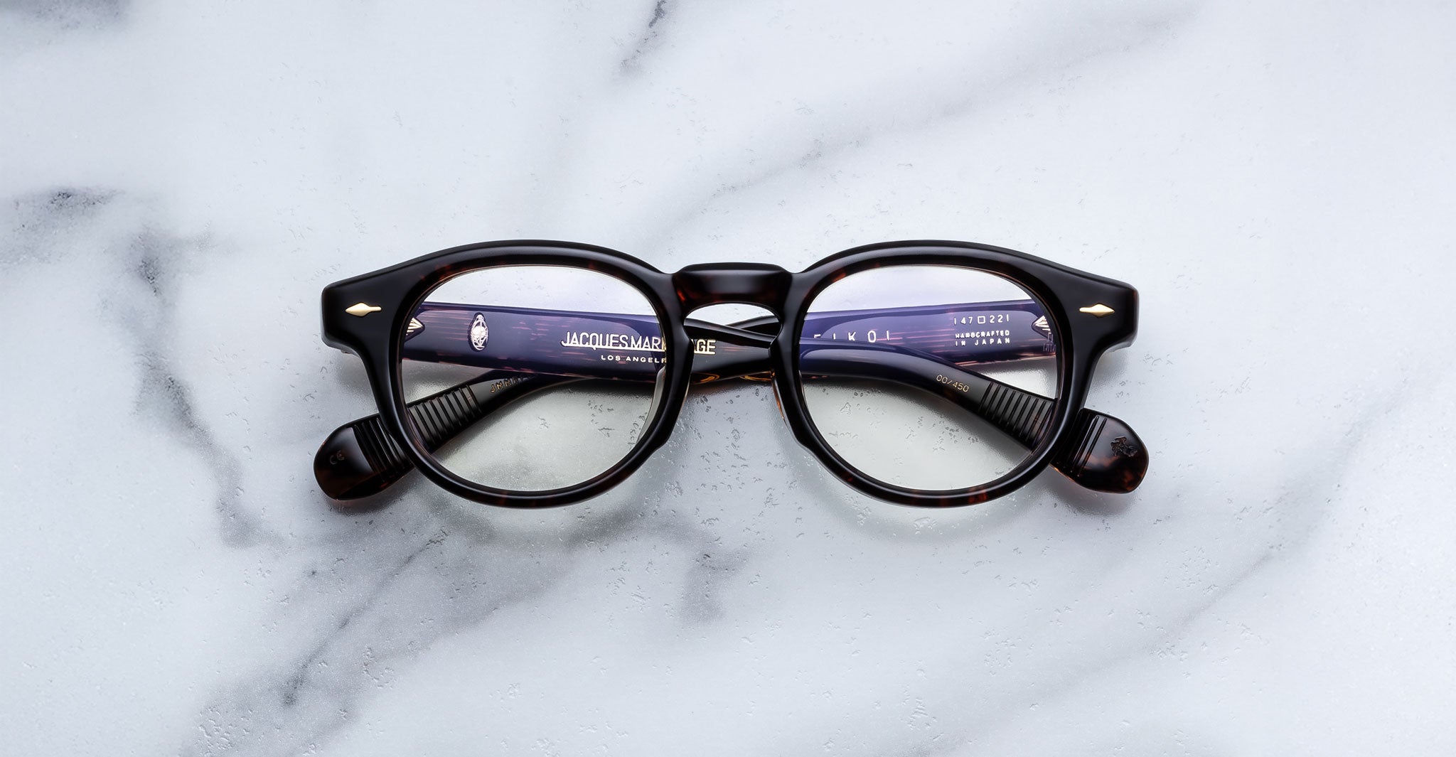 Jacques Marie Mage Eiko round tortoiseshell eyeglasses with crossed arms, viewed from above.