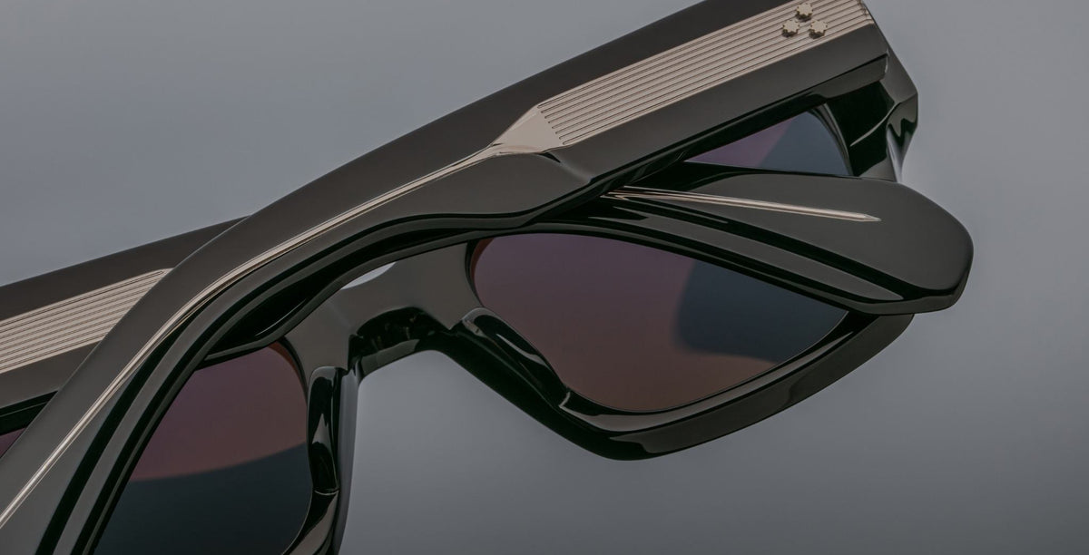 Close-up of stacked Jacques Marie Mage Enzo black sunglasses with dark lenses, viewed from the back.