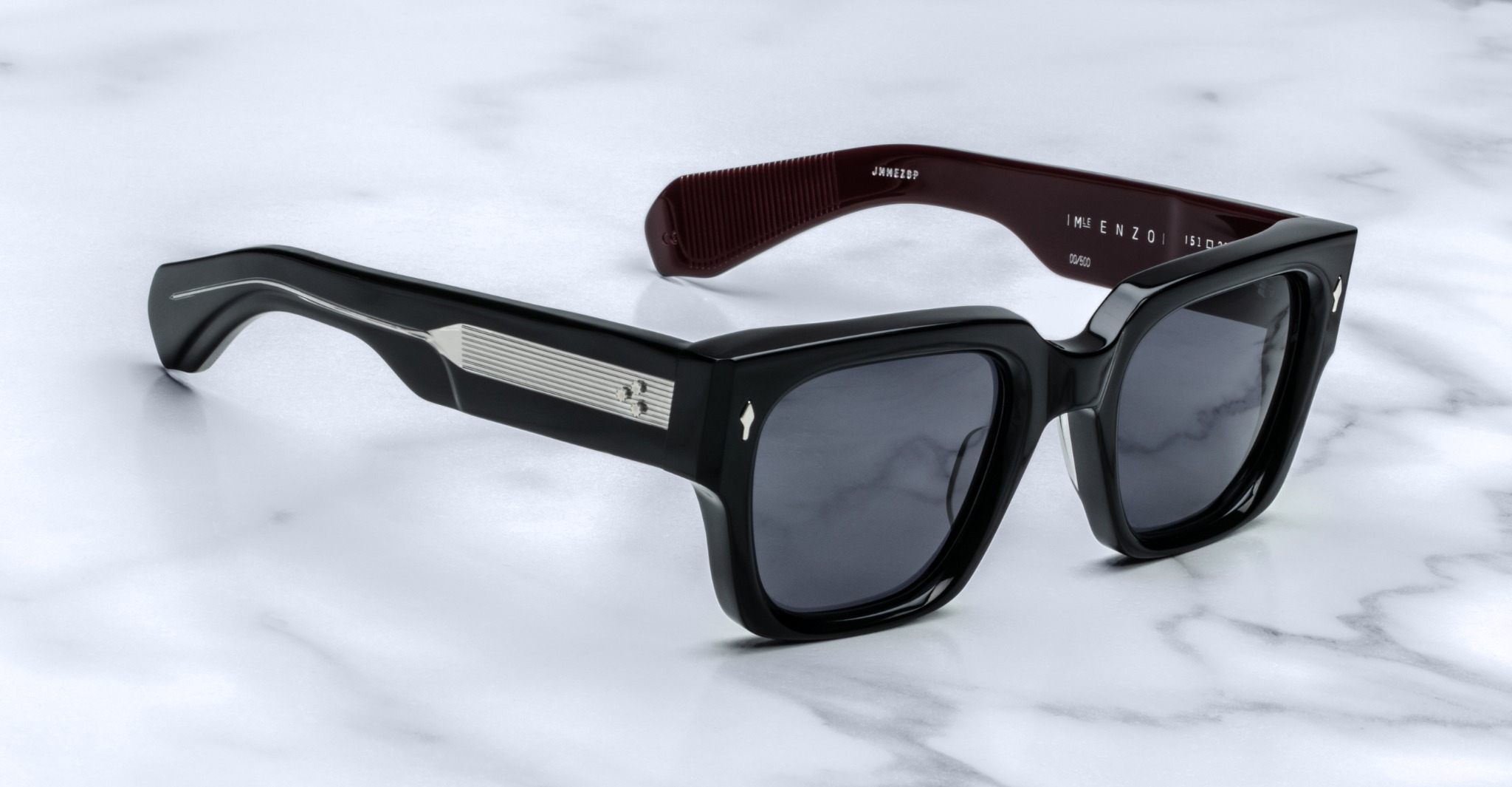 Jacques Marie Mage Enzo black rectangular sunglasses with dark lenses and silver accents, shown from above.