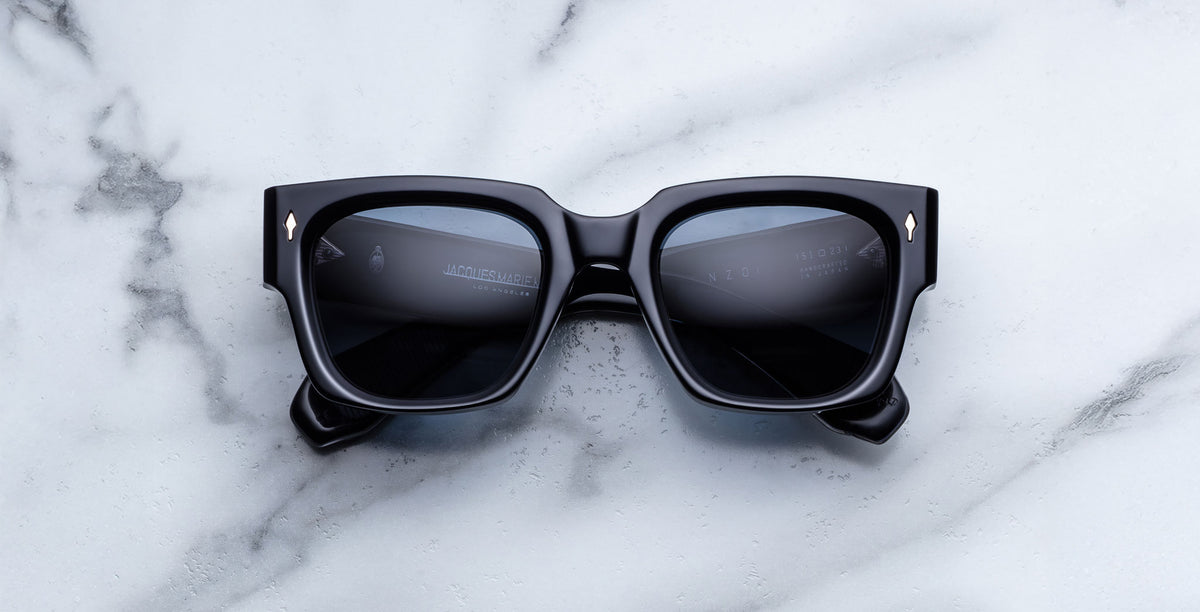 Jacques Marie Mage Enzo black rectangular sunglasses with dark lenses, viewed from above.