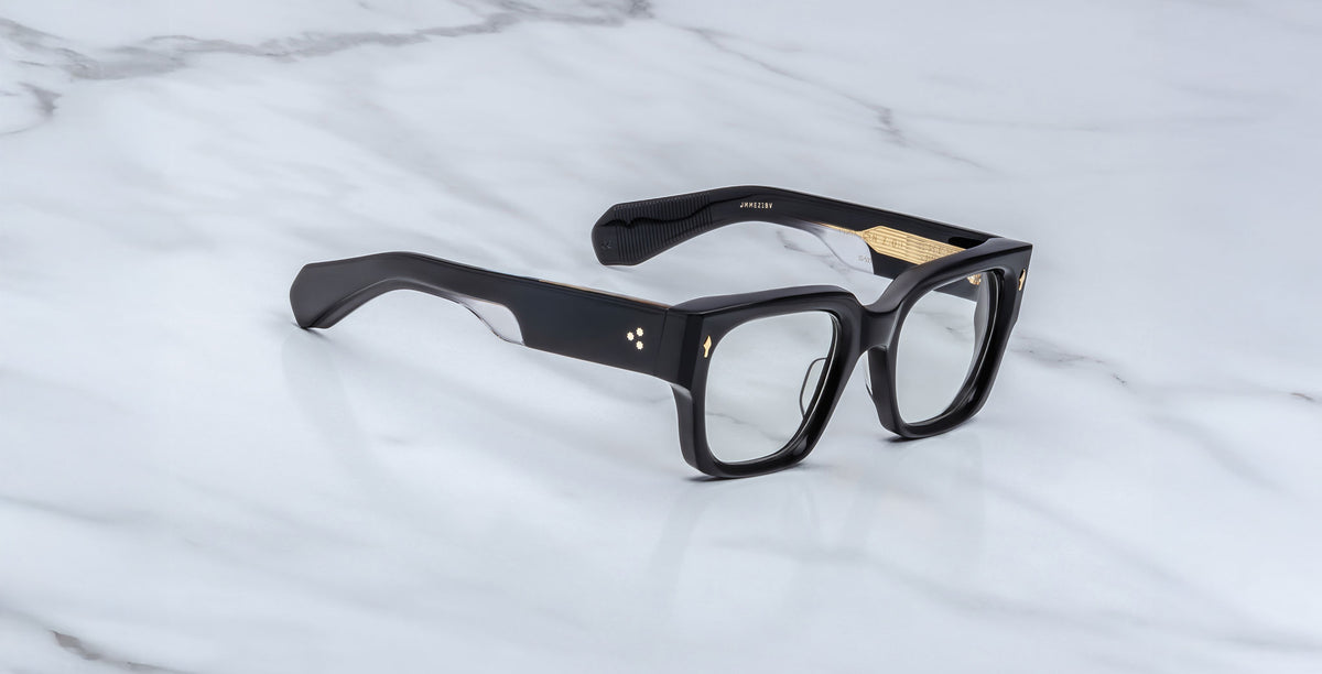 Jacques Marie Mage Enzo black rectangular eyeglasses with gold accents, top view, product displayed on marble.