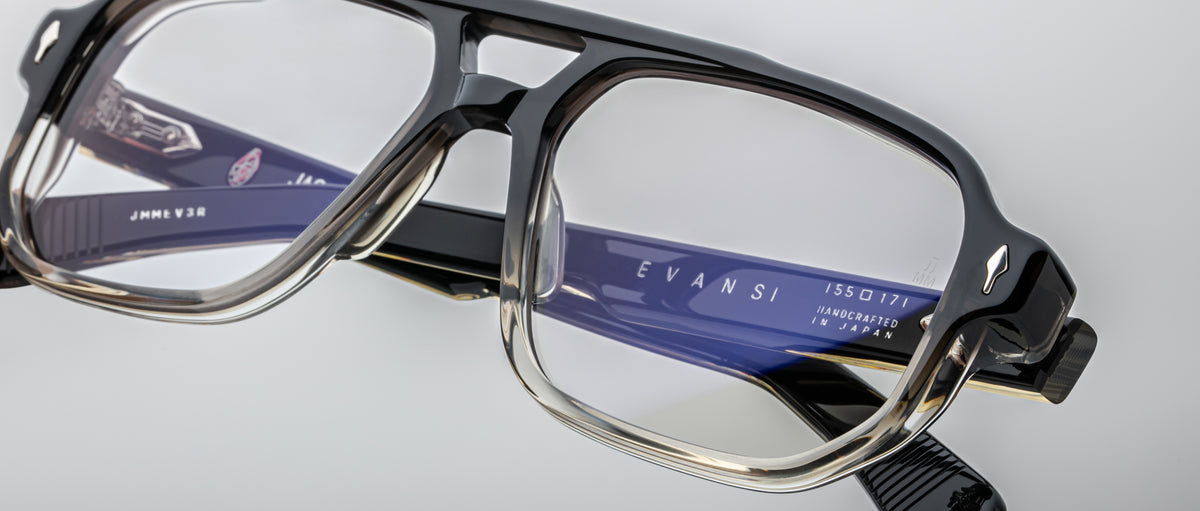 Close-up of Jacques Marie Mage Evans optical glasses with black and clear handcrafted oversized acetate frame and visible branding on the blue inner temple.