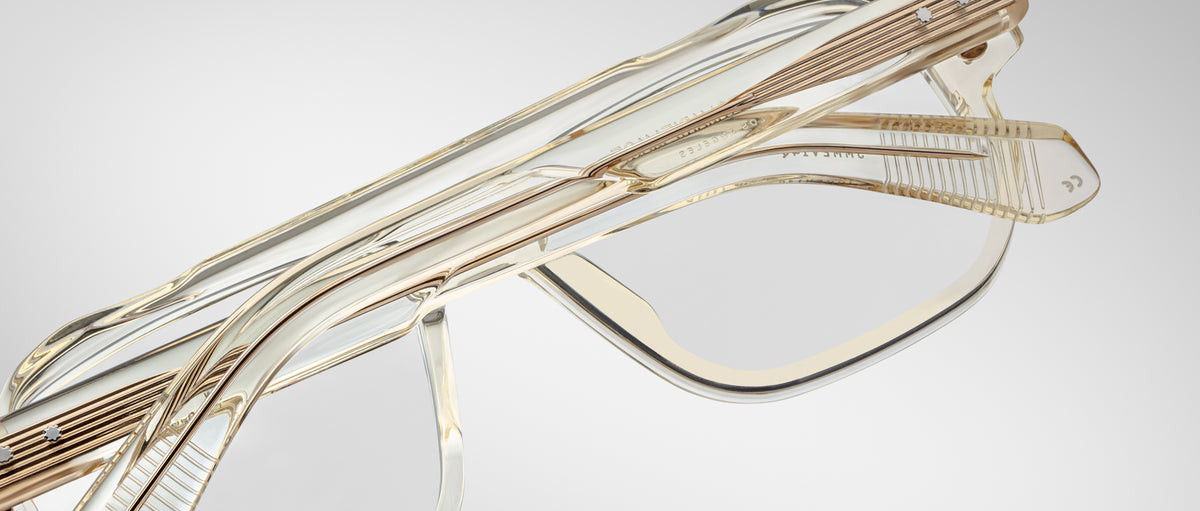 Close-up of two pairs of Jacques Marie Mage Evans optical glasses, featuring gold accents and oversized acetate frames, stacked on each other against a plain background.