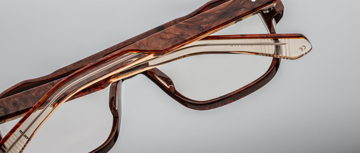 Two pairs of Jacques Marie Mage Evans optical glasses with brown tortoiseshell oversized acetate frames are stacked atop each other against a gray background.