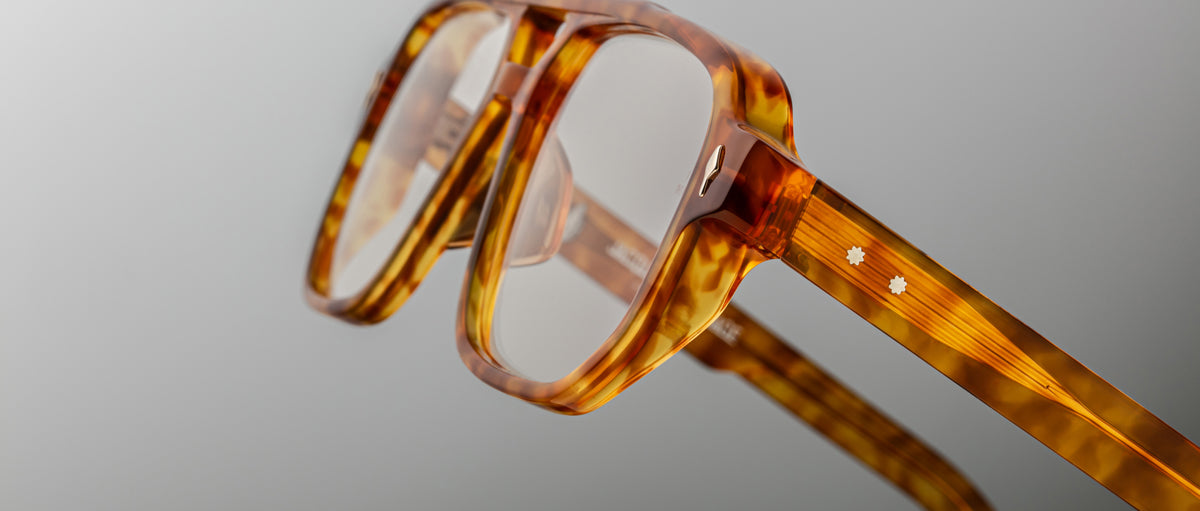Close-up of Jacques Marie Mage Evans optical glasses showcasing a handcrafted oversized acetate frame in tortoiseshell pattern with two small white star-shaped details on the temple.