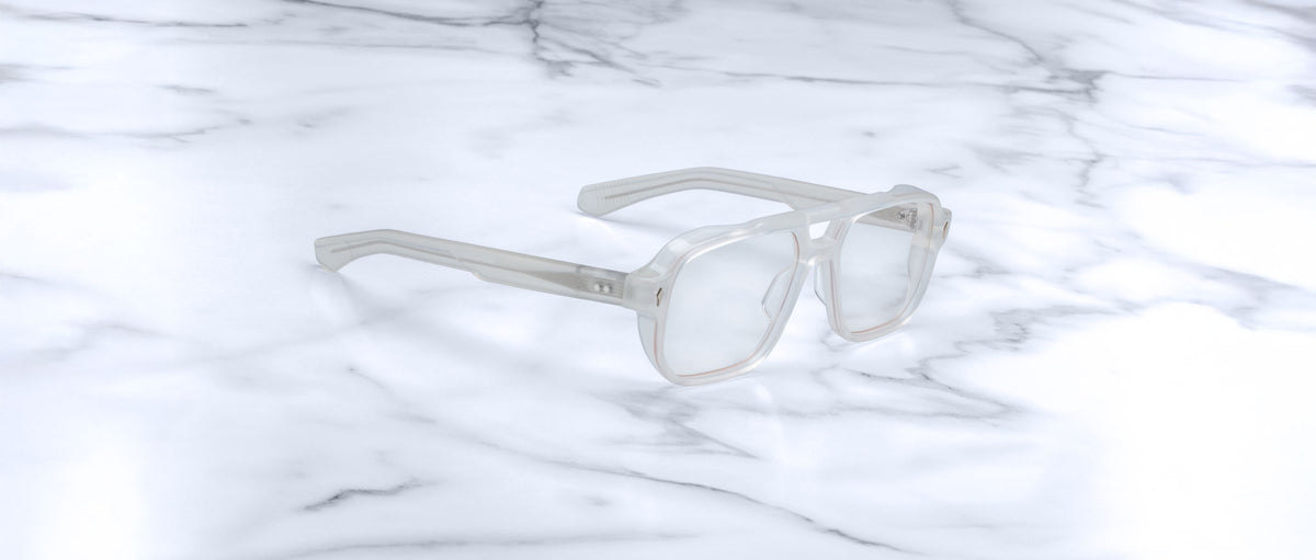 Jacques Marie Mage Evans: Oversized clear rectangular acetate eyeglasses by Jacques Marie Mage, handcrafted and displayed on a white marble surface.