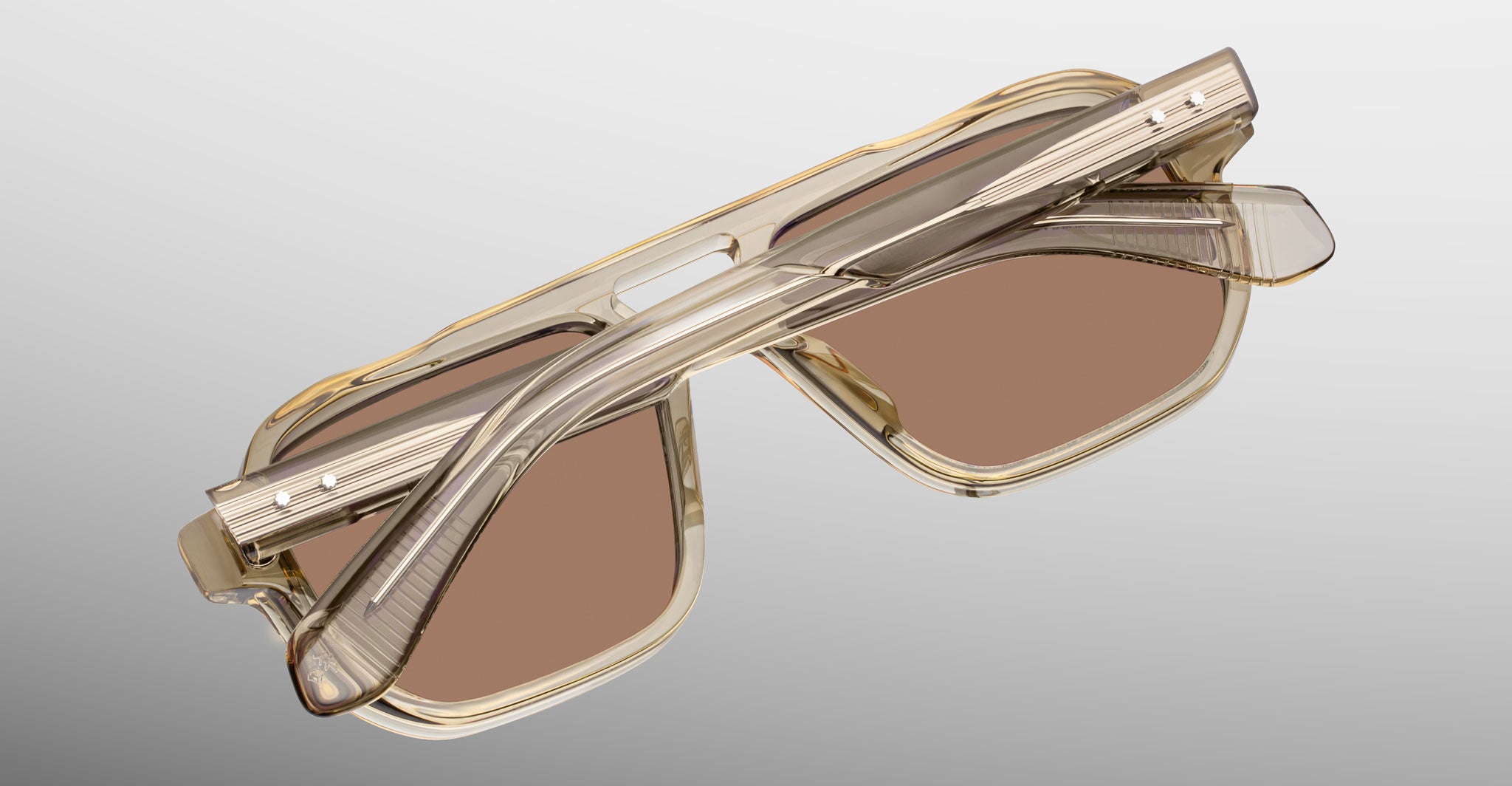 Jacques Marie Mage Evans sunglasses, folded, rectangular shape with translucent beige frames and brown UV lenses, top view.