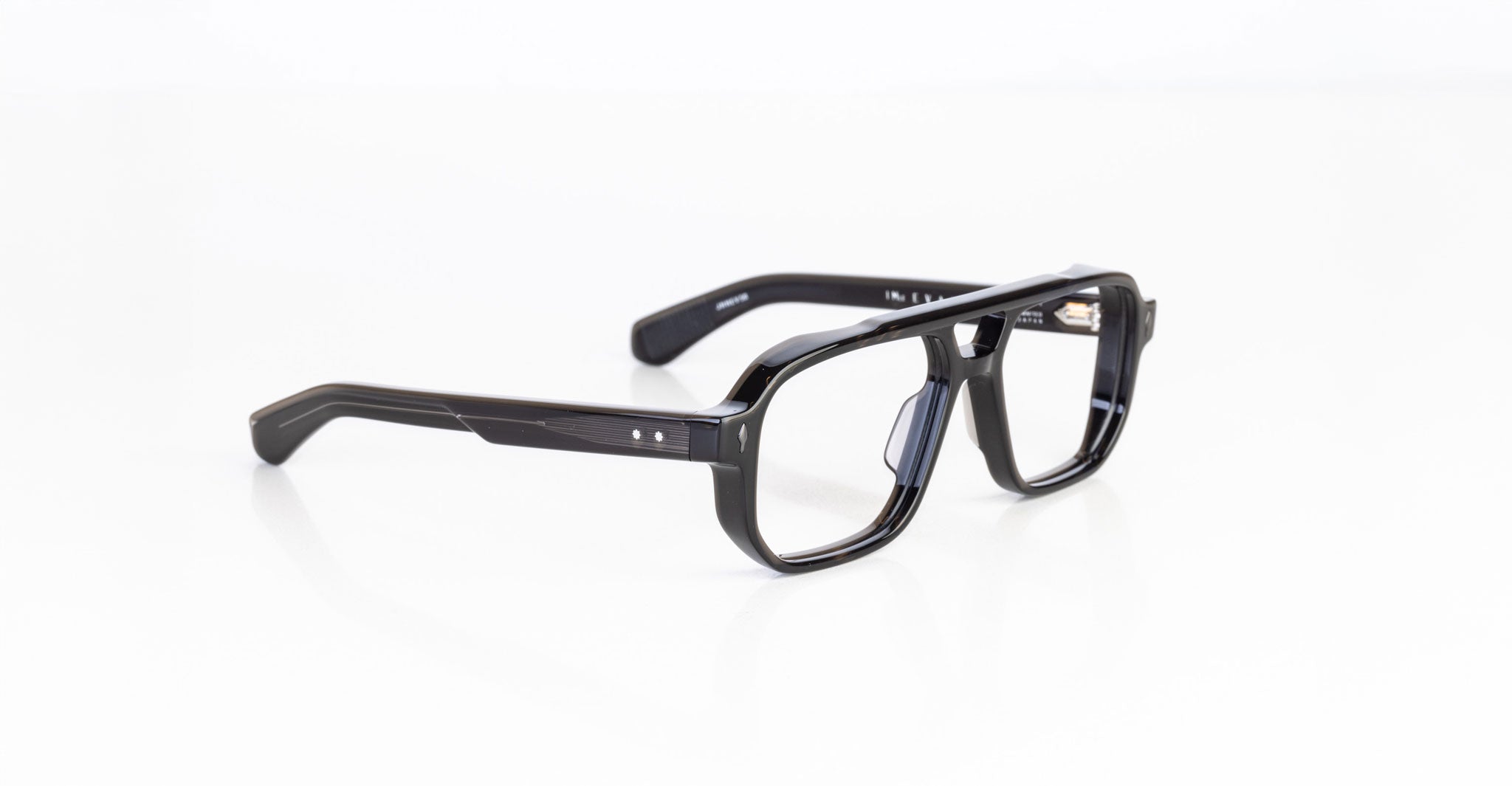 The Jacques Marie Mage Evans are black rectangular eyeglasses with a thick, oversized handcrafted acetate frame by Jacques Marie Mage, elegantly displayed on a white surface.