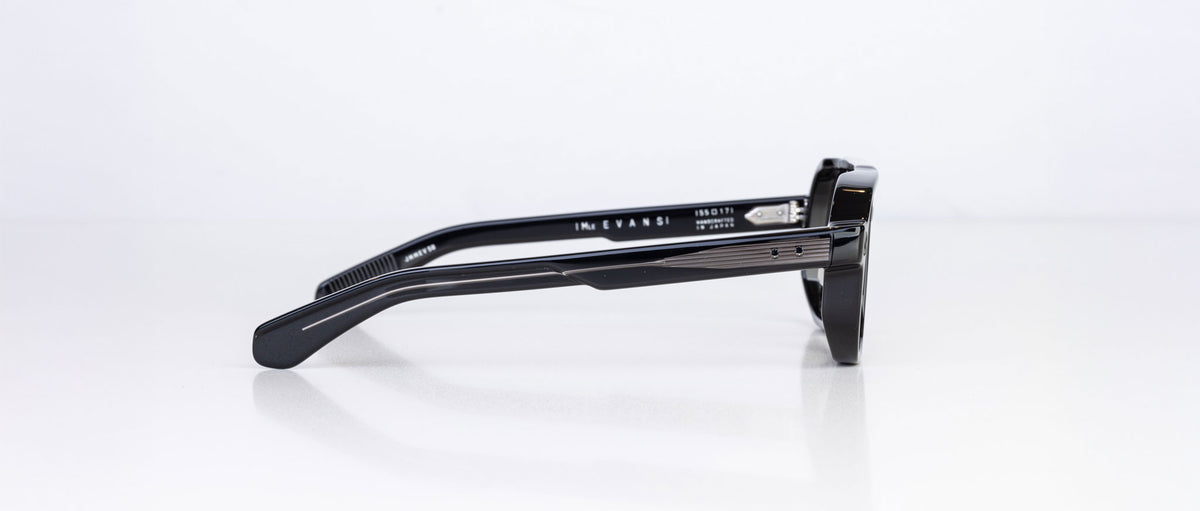 A side view of the Jacques Marie Mage Evans sunglasses showcases their thick, oversized black acetate frame and detailed hinges against a plain white background.