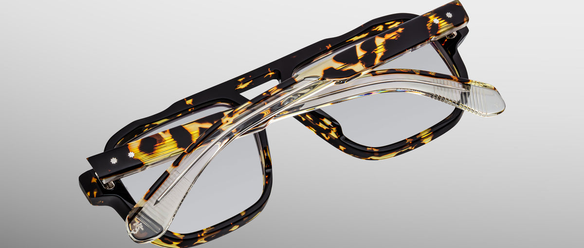 A pair of Jacques Marie Mage Evans tortoiseshell glasses stacked with clear handcrafted optical rectangular frames, both by Jacques Marie Mage, shown on a plain background.