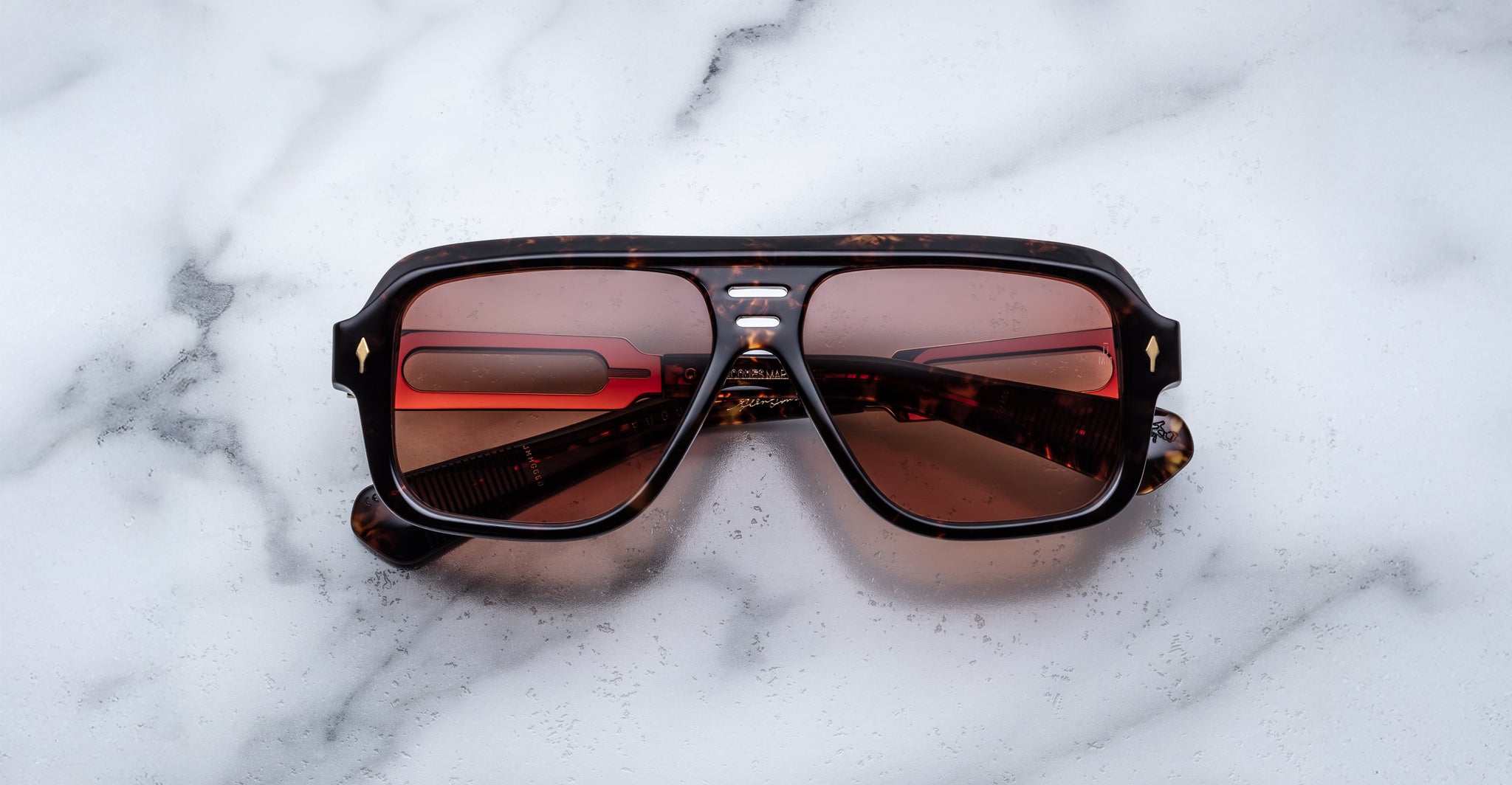 Jacques Marie Mage Fugue sunglasses with red-tinted lenses, top view, featuring bold frames on a white surface.