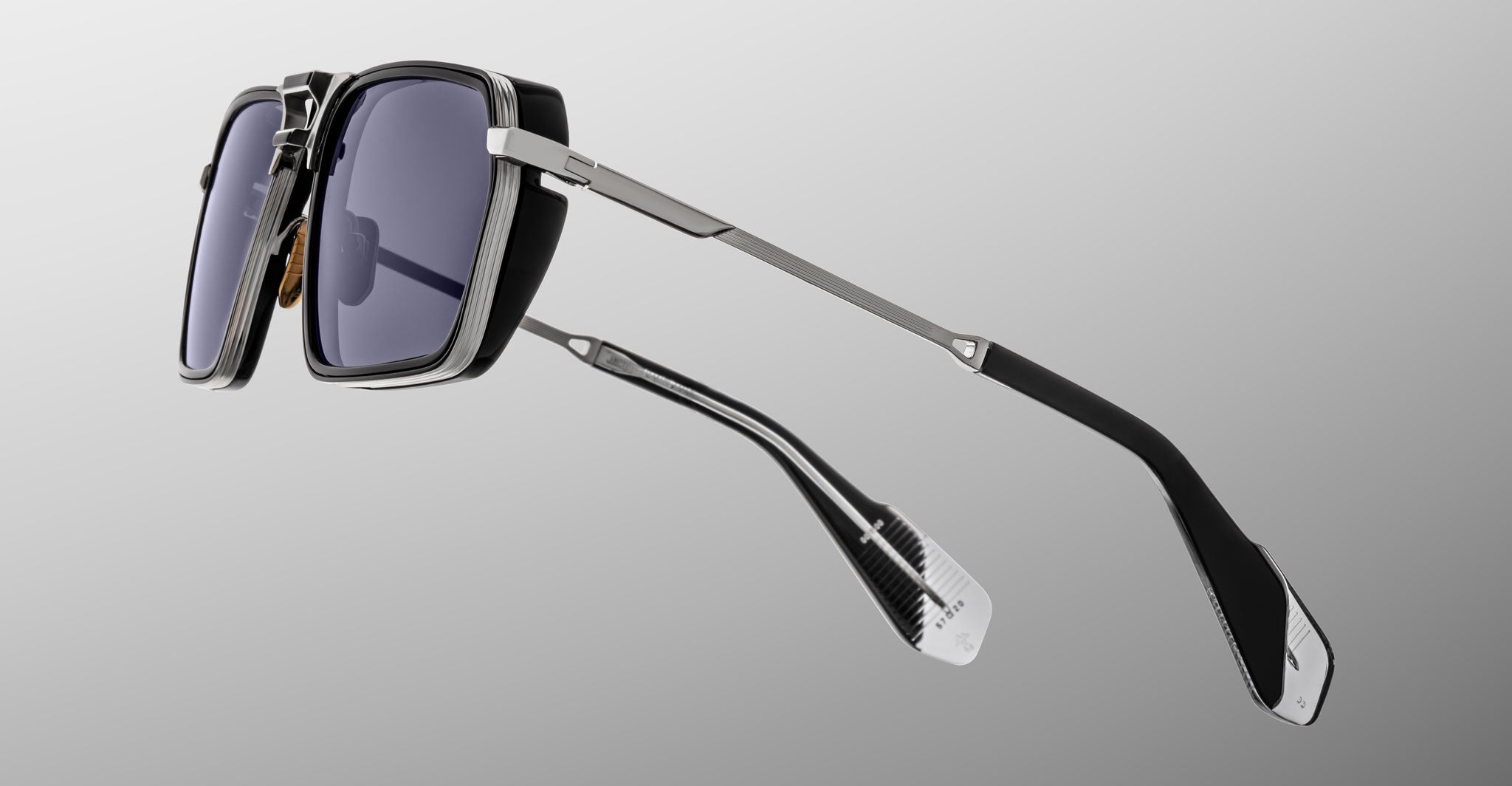 A pair of Jacques Marie Mage GT-R sunglasses featuring modern rectangular thick black frames, dark tinted lenses, and slim metallic arms, photographed against a plain grey gradient background.