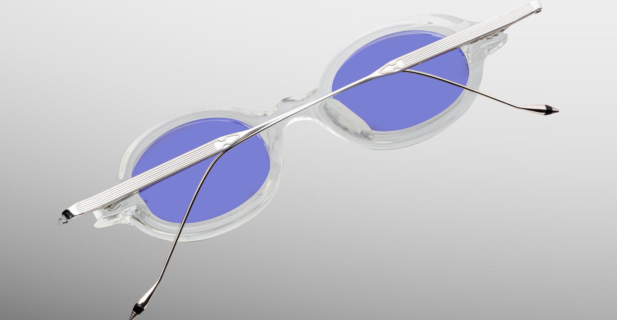 Jacques Marie Mage Balthazar eyeglasses, clear oval frames with blue-tinted lenses and extended arms, front angled view.