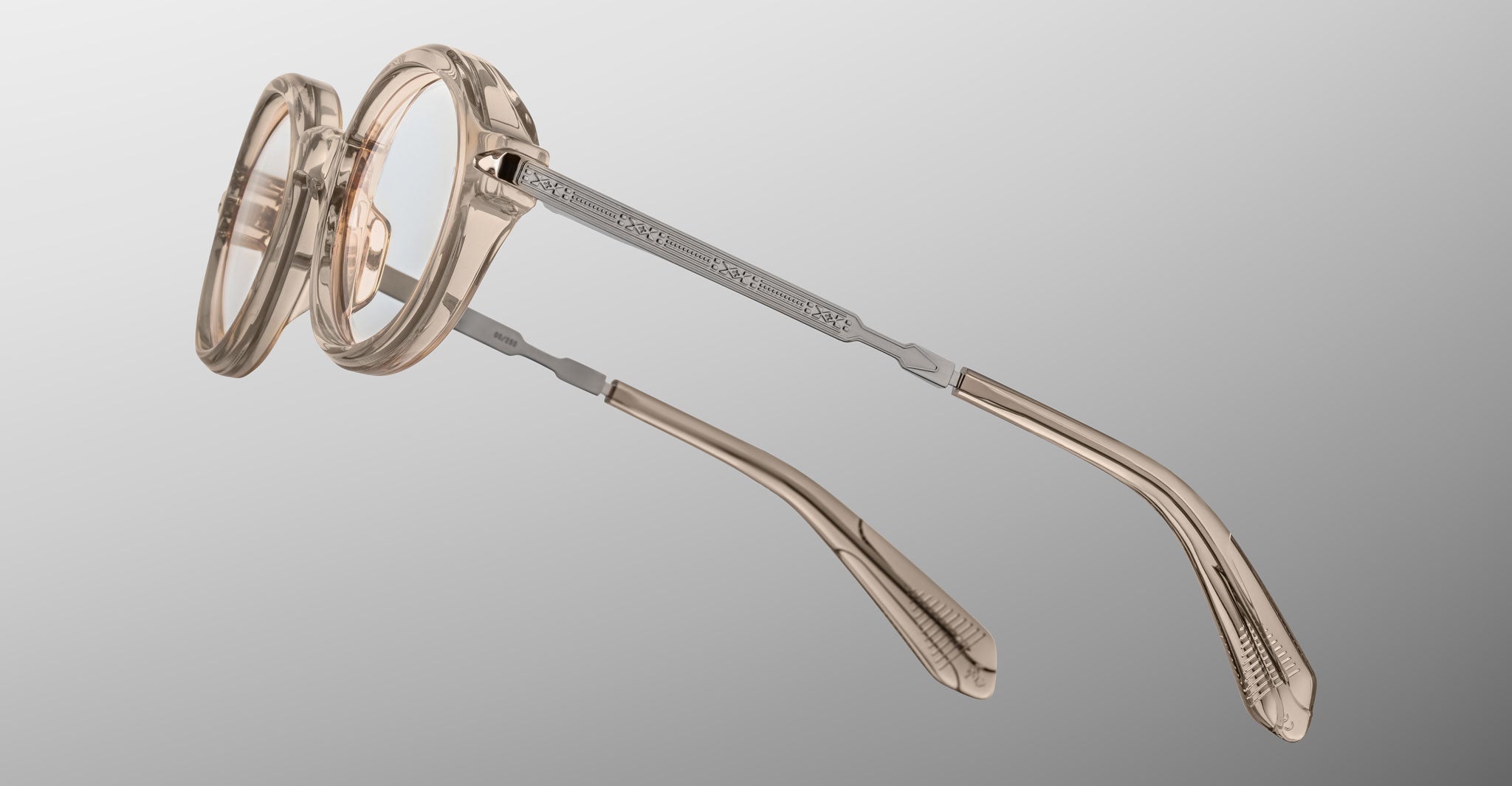 Jacques Marie Mage Hartigan in Sand, round translucent beige acetate eyeglasses shown from a rear side angle, highlighting engraved metal core temples, custom hinge details, and sculpted temple tips with clear demo lenses.