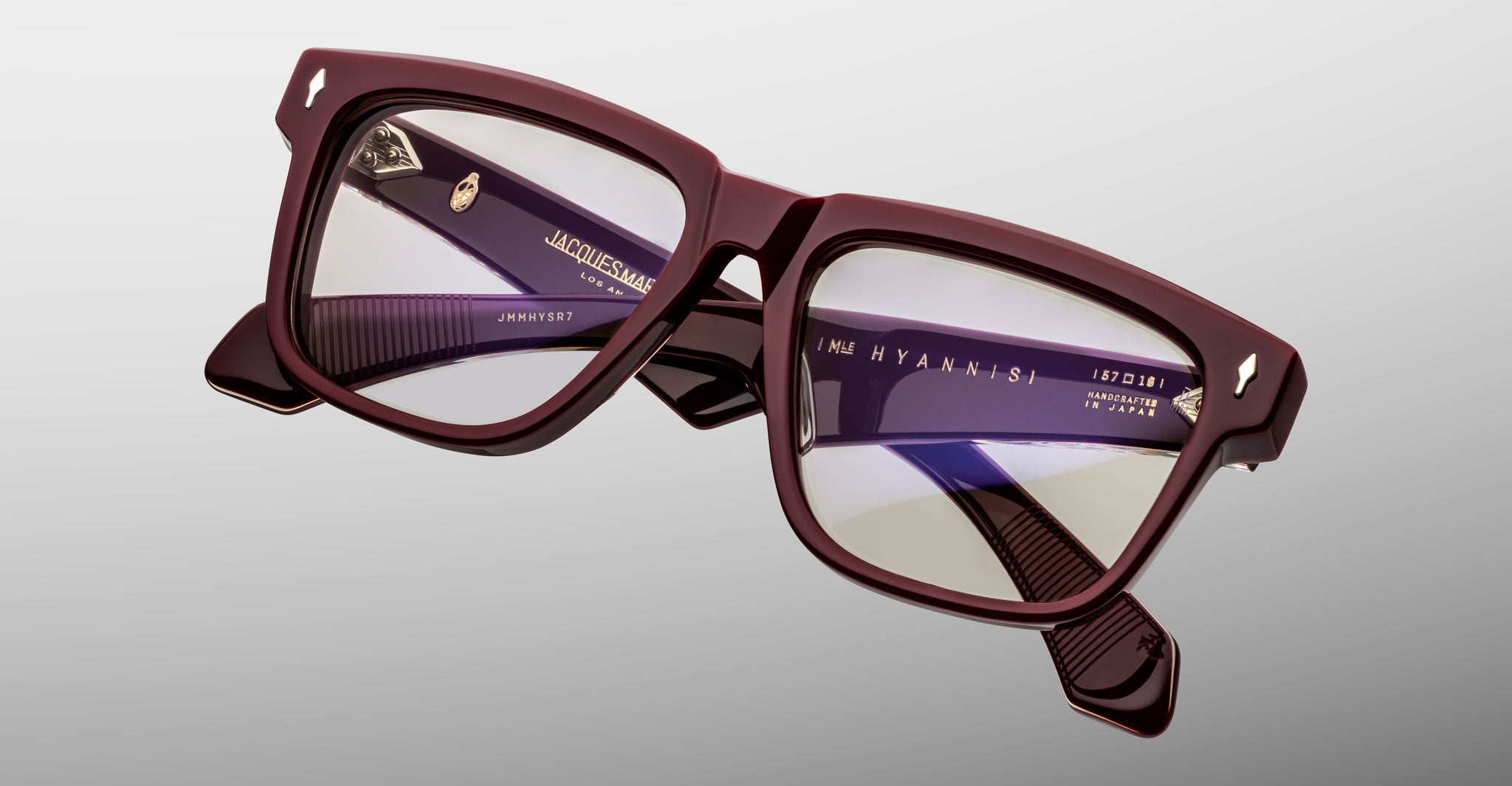 Close-up of Jacques Marie Mage Hyannis in Bordeaux burgundy rectangular eyeglasses with clear lenses; lightweight frames, brand name on inner arms.